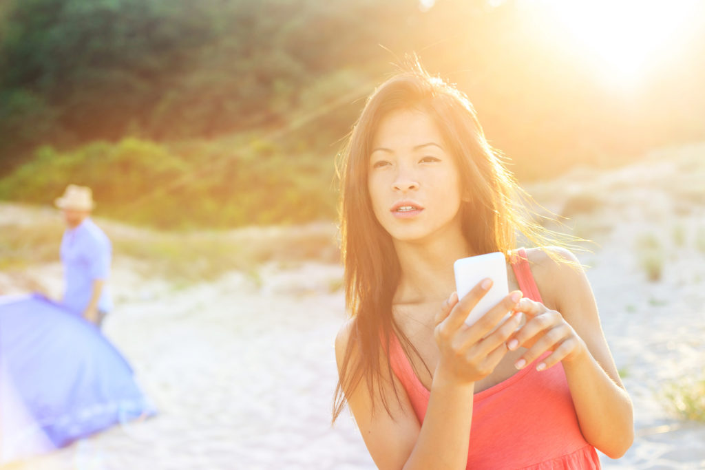 Woman on the beach texting a smart phone
